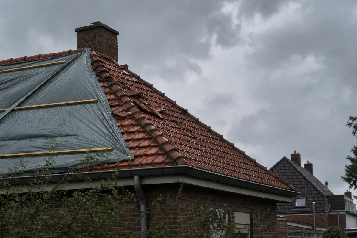 Tuiles déplacées et bâche de protection sur une toiture après un coup de vent dans le Nord